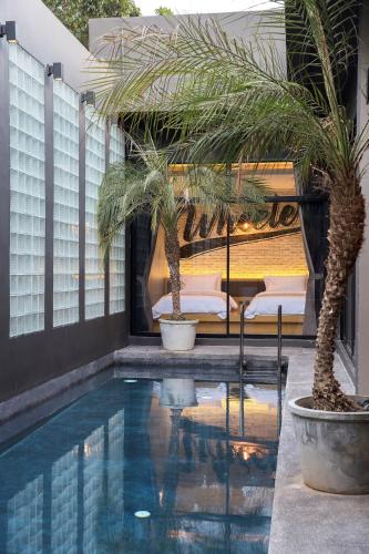a hotel swimming pool with a bed and palm trees at Wheeler Bed &Bike in Bangsaen