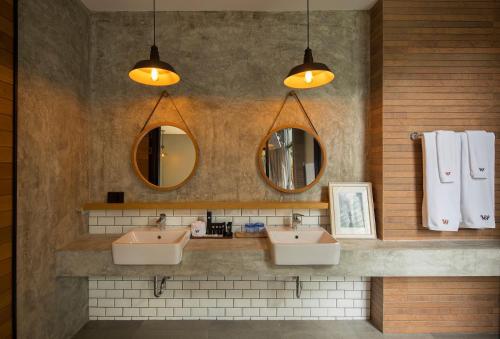 a bathroom with two sinks and two mirrors at Wheeler Bed &Bike in Bangsaen