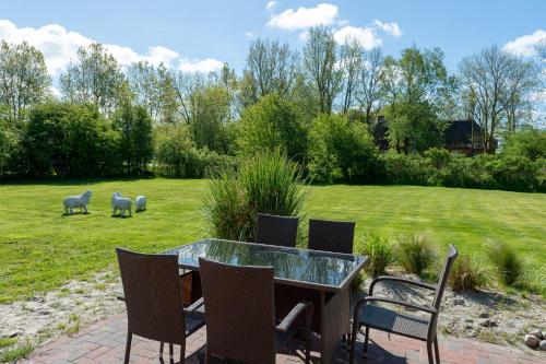 a patio with a table and chairs and sheep in a field at Lehrerwohnung in Tümlauer Koog