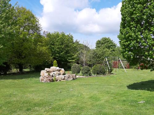 a park with a pile of rocks and a swing set at La grange des lisières in Rouvres