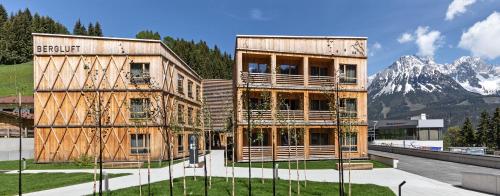 a large building with mountains in the background at Tirol Lodge in Ellmau