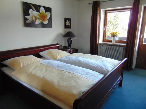 Una cama grande en un dormitorio con ventana. en Landhaus Kogel, en Ofterschwang