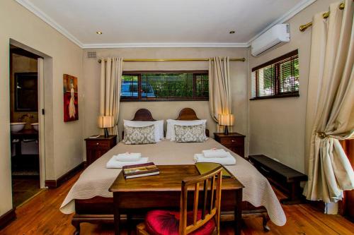 a bedroom with a large bed with a wooden table at Ladera - Vista Self-catering Guesthouse in Paarl