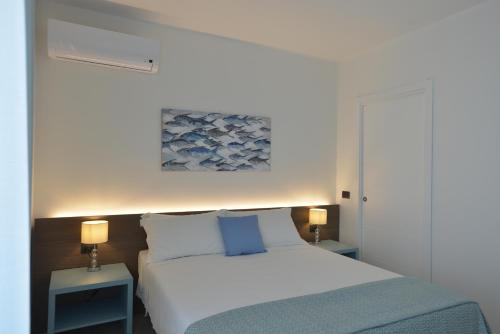 a bedroom with a white bed and two tables with lamps at Milena Suite Apartments in Alghero