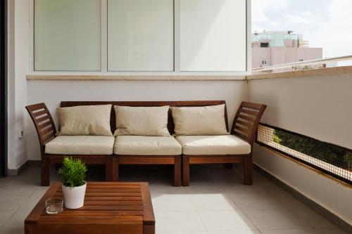 a couch sitting on a balcony with a table at Sunny Luxury Apartments in Tel Aviv