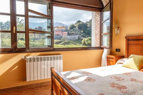 Un dormitorio con una cama y una ventana grande. en El Prau la Iglesia Porrua - Llanes, en Porrúa