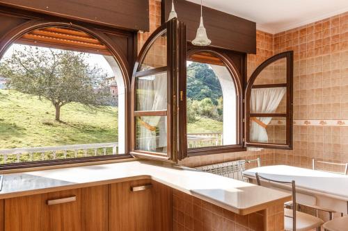 a kitchen with two large windows and a table at El Prau la Iglesia I in Porrúa