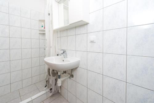 a white tiled bathroom with a sink and a window at Villa Mimoza in Cavtat