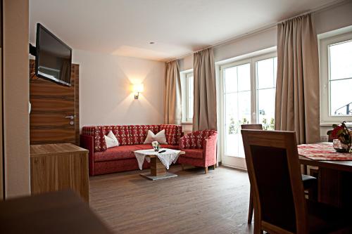 a living room with a red couch and a table at Villa Sepp in Ramsau im Zillertal