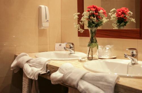 een badkamer met 2 wastafels en een vaas met bloemen bij Hotel El Carmen in Puente-Genil