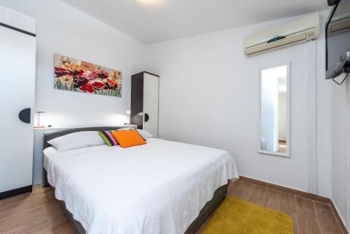 a bedroom with a white bed with an orange pillow at Villa Mimoza in Cavtat