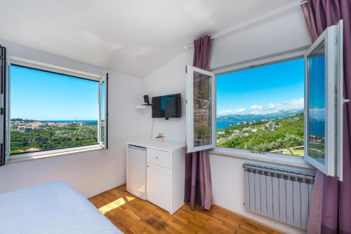 1 dormitorio con ventanas grandes, 1 cama y TV en Villa Mimoza en Cavtat