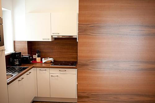 a kitchen with white cabinets and a wooden wall at Villa Sepp in Ramsau im Zillertal