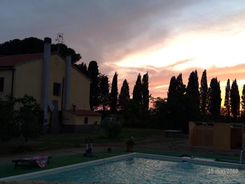 a sunset over a swimming pool in front of a house at Casolare Casa Ricci in Riotorto