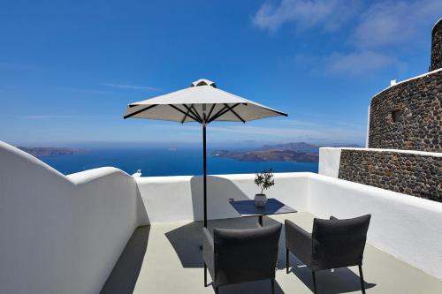 a table and chairs on a balcony with an umbrella at Petit Palace Suites in Fira