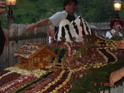 a man standing over a cake with a house on it at Hotel Gomagoierhof in Stelvio