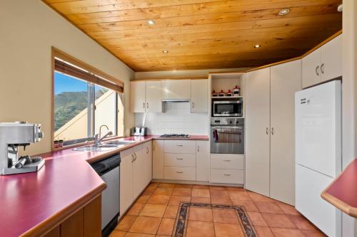 a kitchen with white cabinets and a wooden ceiling at Amazing View Home in Queenstown