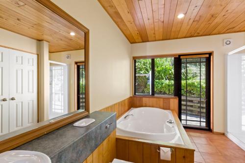 baño con bañera y espejo grande en Amazing View Home en Queenstown