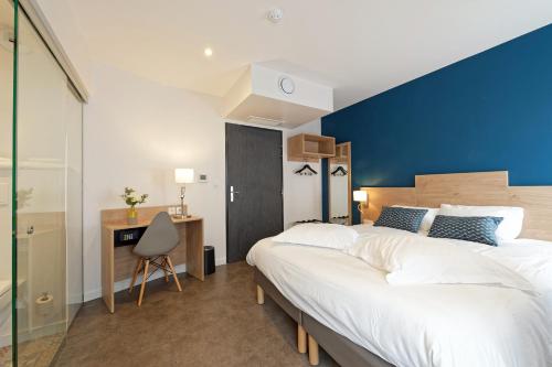 um quarto com uma cama grande e uma parede azul em Contact Hôtel de la Gare et son restaurant Côte à Côte em Autun