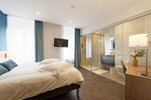 a bedroom with a large bed and a bathroom at Contact Hôtel de la Gare et son restaurant Côte à Côte in Autun