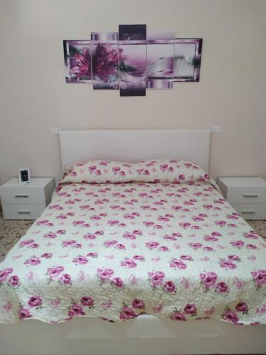 a bedroom with a bed with a floral comforter at Aspra al delfino blu in Bagheria
