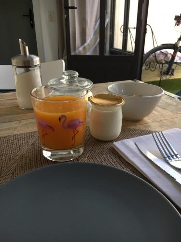 a table with a glass of orange juice and bowls at Ô 36 Rempart Sud B&B in Aigues-Mortes