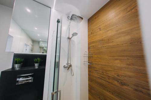 uma casa de banho com um chuveiro e uma porta de madeira em Hypnotize Apartment em Konin