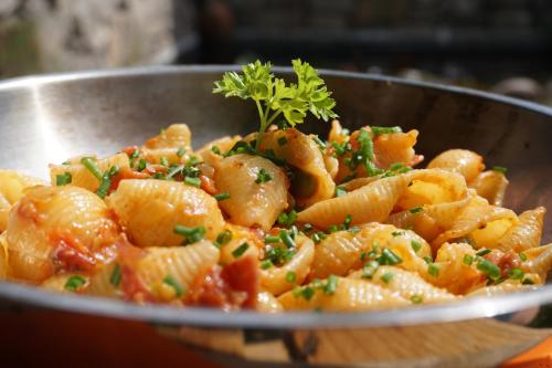 a metal bowl of pasta with a parsley garnishment at Guesthouse Dolomiten in Egna