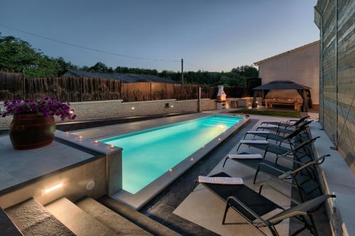 a swimming pool with chairs next to a house at Villa Patrick-Luxury stone house in the center of Istria in Pazin