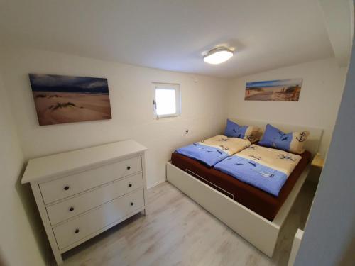 a small bedroom with a bed and a dresser at Haus auf der alten Düne 2 in Prerow