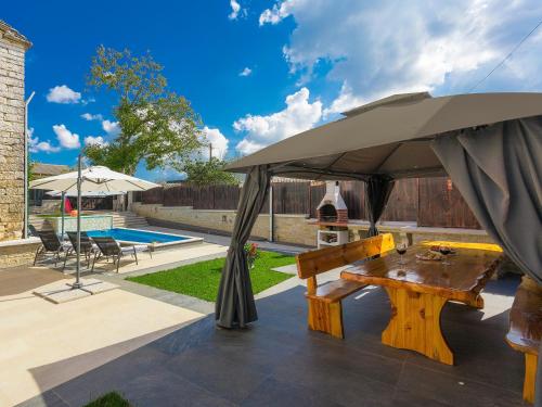a picnic table under an umbrella next to a pool at Villa Patrick-Luxury stone house in the center of Istria in Pazin