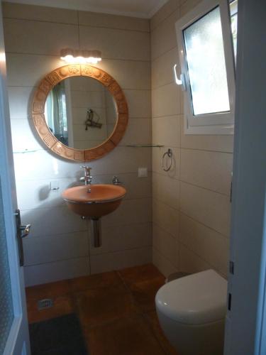 y baño con lavabo, espejo y aseo. en Athina Apartments en Arillas
