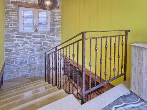 a staircase in a home with yellow walls and a window at Villa Patrick-Luxury stone house in the center of Istria in Pazin