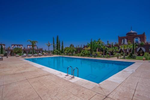 a swimming pool at a resort with a building in the background at Taj Atlas Wellness Boutique Hôtel & Spa in Amizmiz