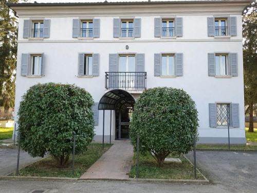 a white building with two trees in front of it at Hotel Sporting in Campagnola Emilia