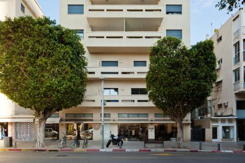 wysoki biały budynek z drzewami przed nim w obiekcie Sunny Luxury Apartments w Tel Awiwie