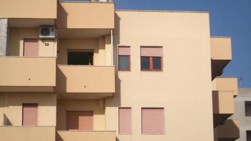 a tall white building with windows and a blue sky at Bilocale Punta Rosa - Fronte Spiaggia in Otranto