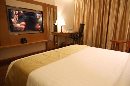 a hotel room with a bed and a flat screen tv at Regenta Central RS Chennai OMR SIPCOT in Chennai