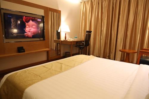 a hotel room with a bed and a flat screen tv at Regenta Central RS Chennai OMR SIPCOT in Chennai