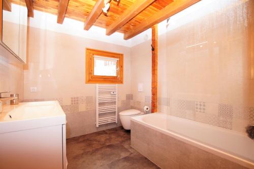 a bathroom with a tub and a toilet and a sink at Chalet du Pre in Séez