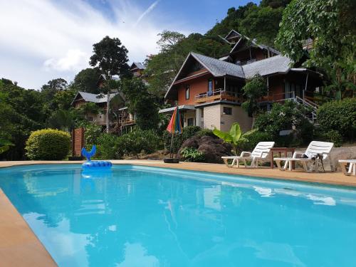 a swimming pool in front of a house at Phitharom PP Resort in Phi Phi Islands