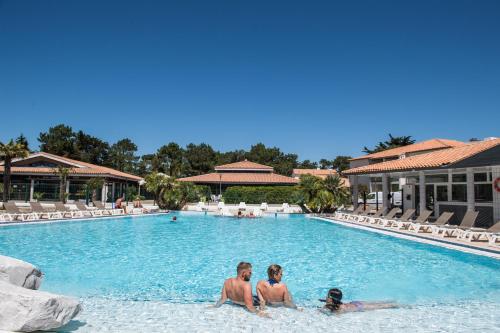 three people sitting in the swimming pool at a resort at Camping Les Grenettes in Sainte-Marie-de-Ré