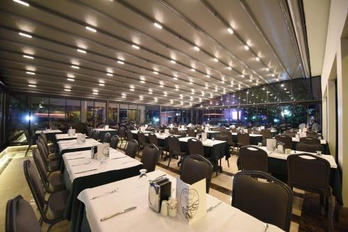 uma sala de jantar com mesas e cadeiras brancas em Herakles Thermal Hotel em Pamukkale