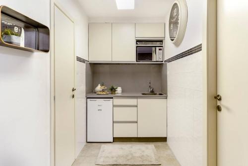 a kitchen with white cabinets and a clock on the wall at Havatselet 19 By Isrentals in Jerusalem