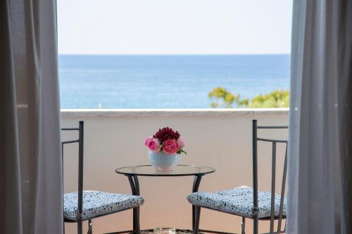 two chairs and a table with a vase of flowers on a balcony at Hotel La Mandorla in Ischia