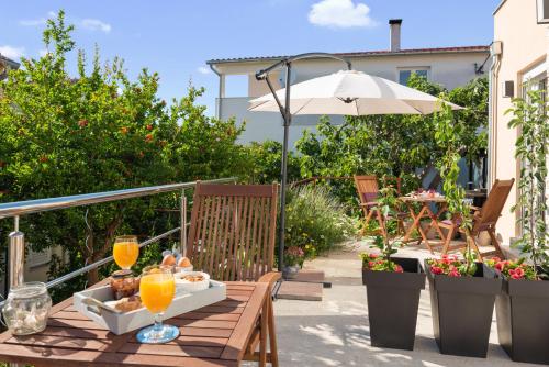 a wooden table with drinks and an umbrella on a patio at Apartments Stella Mariela in Šibenik