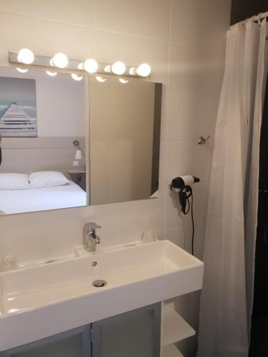 baño con lavabo y espejo grande en Hotel Cote et Lac, en Biscarrosse