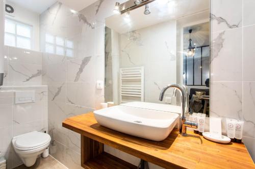 a white bathroom with a sink and a toilet at CMG Oberkampf/ Charonne C in Paris