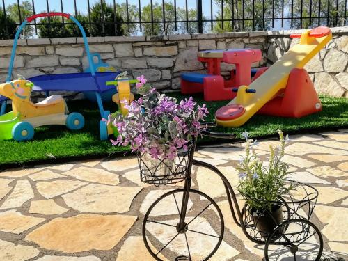 a bicycle with flowers in a playground with toys at Eleftheria's Apartments in Eratini