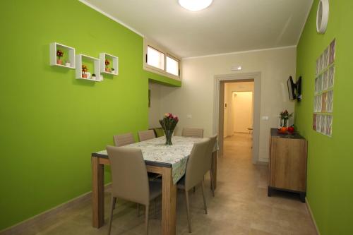 ein Esszimmer mit grünen Wänden sowie einem Tisch und Stühlen in der Unterkunft Porte Maqueda in Palermo